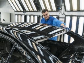 Mitarbeiter prüft die Qualität einer lackierten Karosserie im Decklack-Finish